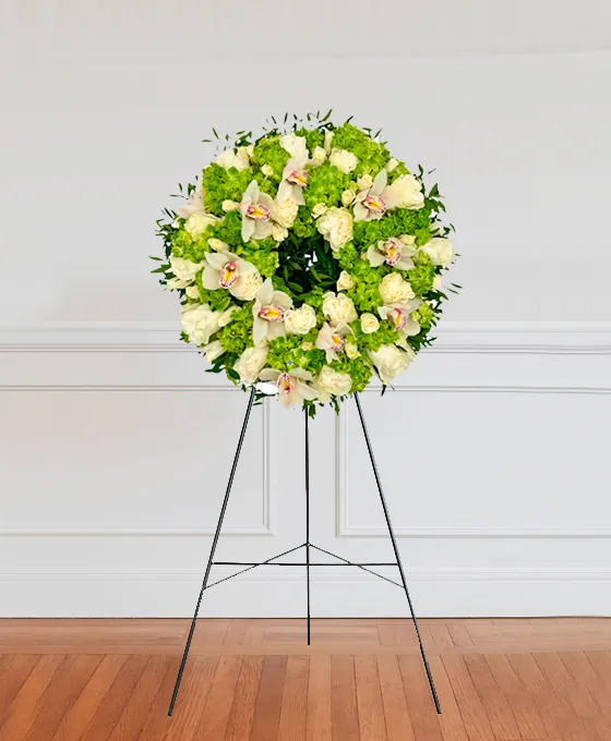Green and white funeral wreath on a stand