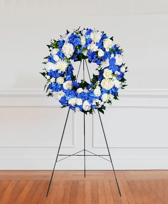 Blue and white funeral wreath on a stand